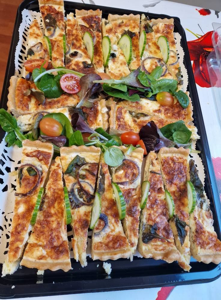 A platter of quiche slices with salad and tomatoes