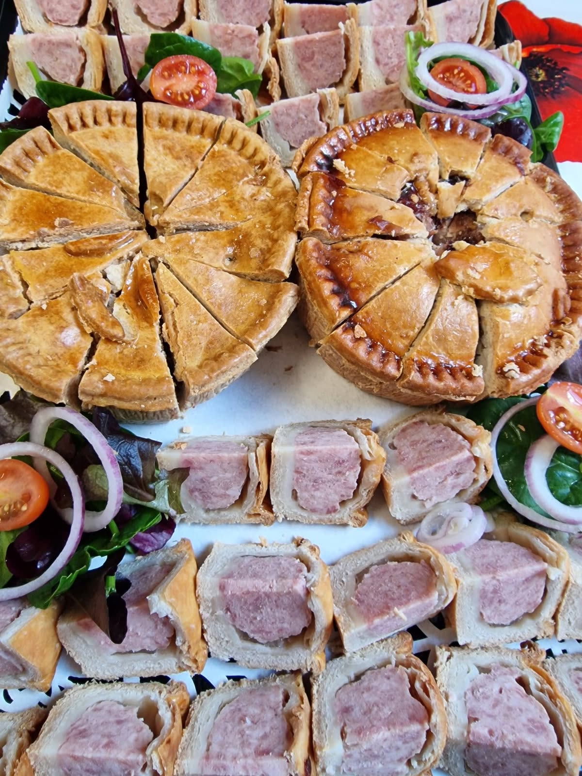Pork pies and sausage rolls on a platter with salad