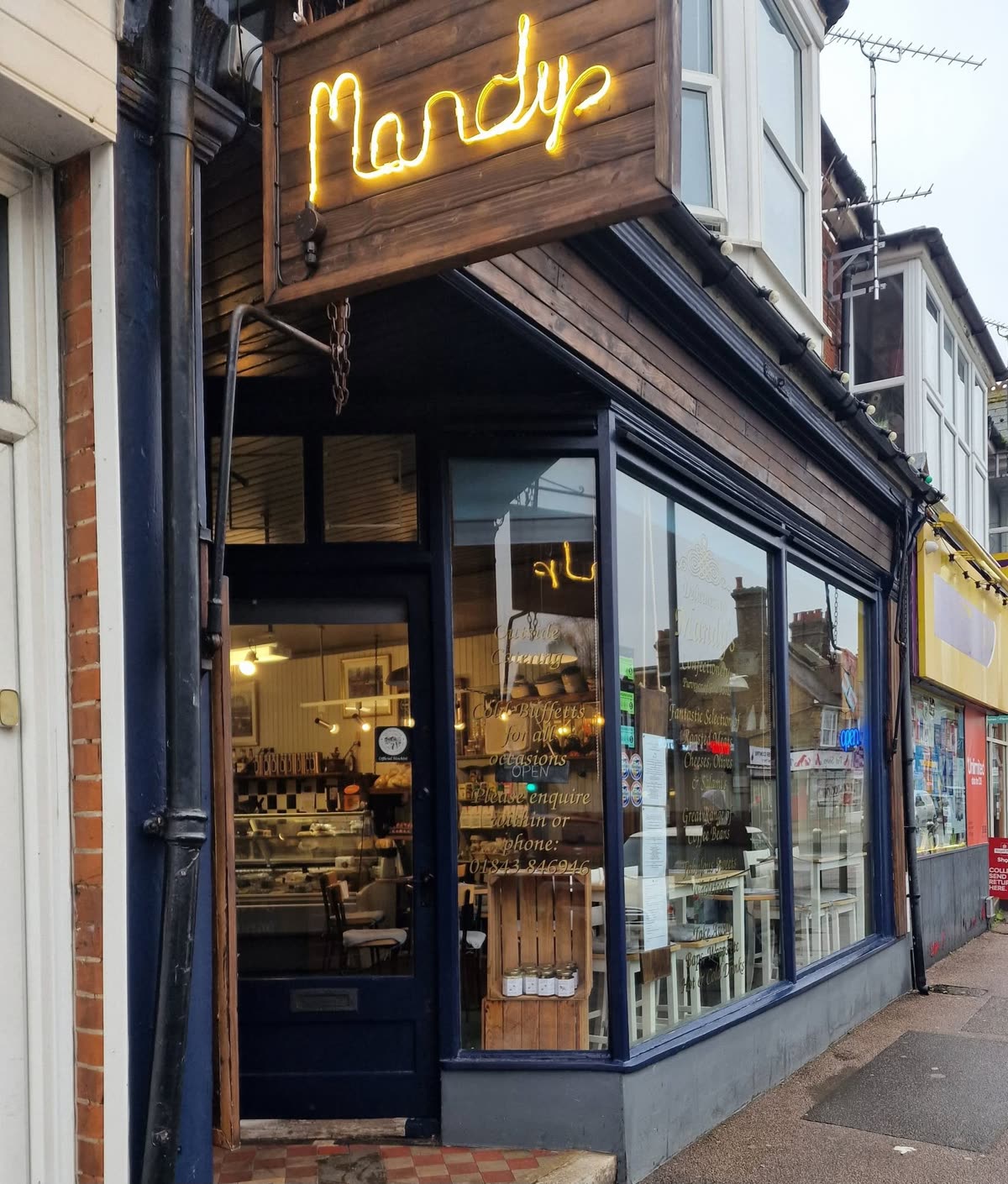 The dark blue shop front on Station Road with the neon Mandy's sign